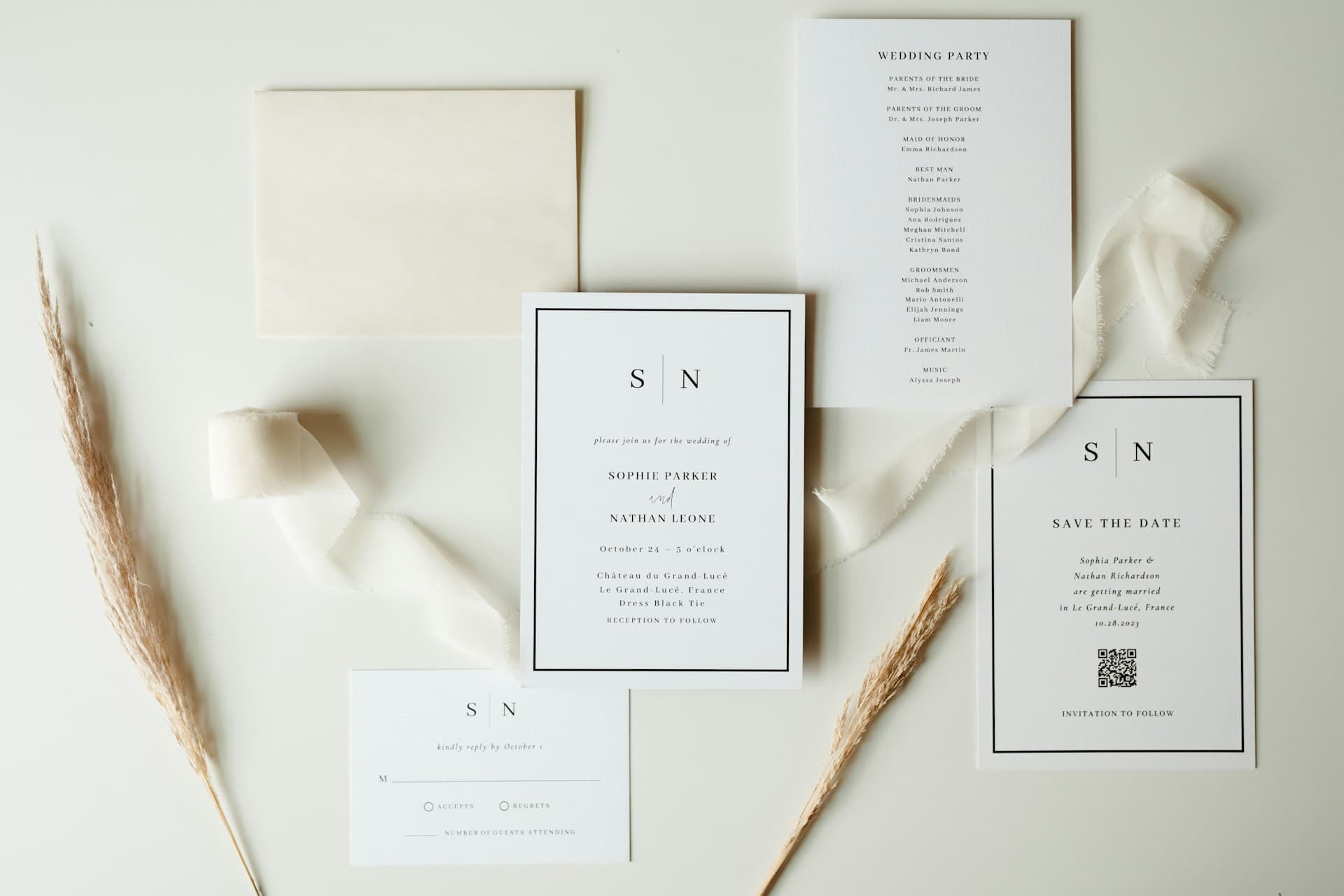 Elegant wedding stationery flat lay: invitation suite, RSVP card, and dried pampas grass on cream background.